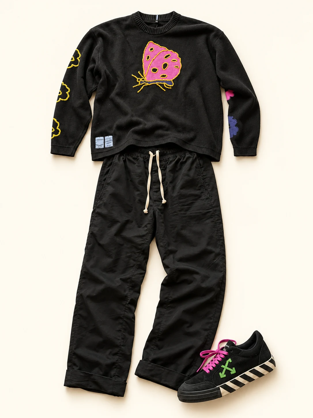 An outfit flat lay with an MCQ butterfly sweater, black Rick Owens trousers and an Off-White sneaker